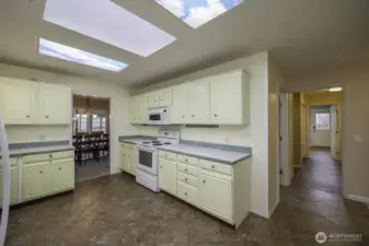 A view of the kitchen with access to the dining room to the left, pantry, laundry, garage, and side door exit.