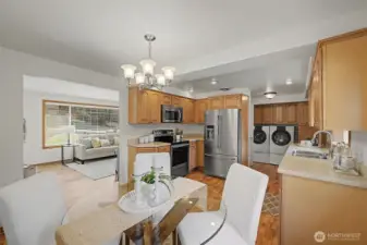 Kitchen with ample cabinetry, stainless appliances, and an adjacent dining area, opening to the living room.