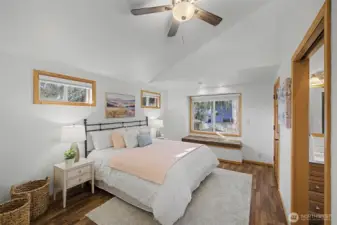 Spacious primary suite with vaulted ceilings, laminate flooring, and a built-in window seat that brings in beautiful natural light and creates a quiet retreat.