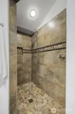 Large walk-in tile shower with mosaic floor, built-in niche, and updated fixtures, offering both function and a clean, timeless look.