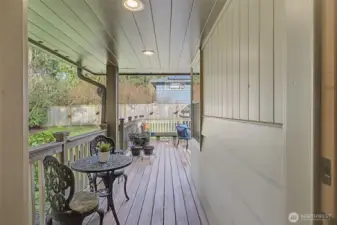 Private covered porch off the primary suite, ideal for morning coffee or quiet outdoor time, overlooking the fenced yard and mature landscaping.