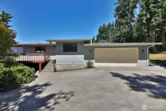 South side of your home. This driveway runs along the south side of your home. 2 car garage. Main entrance is up those stairs you see. The window between the stairs and garage belongs to one of the additional flex rooms.