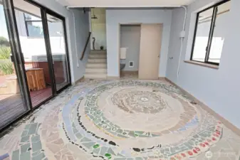 Custom tiled Spiral design in the room that joins the main house to the Primary Suite Guest Space. Sliding doors take you to the deck. Stairs lead you to the Primary Suite.