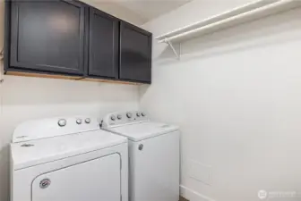 Downstairs laundry room with storage and hanging shelf.