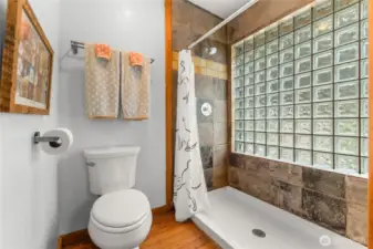 Bright, updated bath with glass block window, slate tile accents, and spacious walk-in shower—simple, sturdy, and stylish