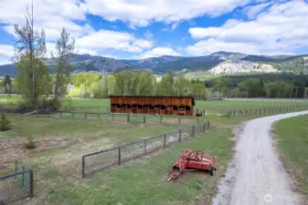 Pastoral setting; graveled ranch road, classic stall barn, and wide-open pasture—ready for livestock, legacy, or both