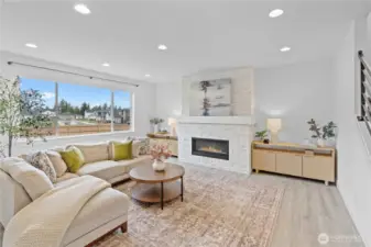 The spacious living room features a sleek linear gas fireplace with a full-height tile surround, and oversized windows that flood the space with natural light.
