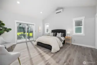 Main floor primary suite, with sliding glass door to the patio beyond.  Vaulted ceiling, mini ductless split AC, plus radiant in-floor heat.