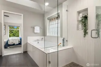 Spa-inspired primary bath features soaking tub and frameless glass shower.