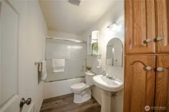 Main full bath with pedestal sink, sliding shower door and linen closet