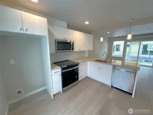 Kitchen with local manufactured cabinets and looking back to living with slider to spacious deck
