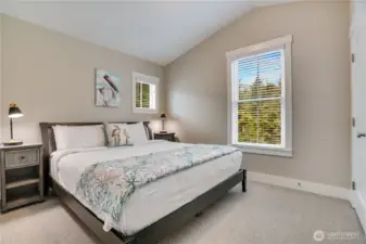 The vaulted ceiling in the bright and spacious primary bedroom enhances the sense of openness.