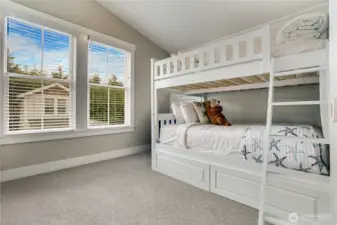 The second bedroom has sunny windows, a full-size bunk bed with storage drawers, and a vaulted ceiling that adds a light, airy feel.