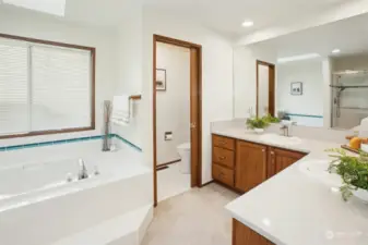 Refreshed primary en suite with new flooring, countertops, mirrors, rolling shower door, shower head and sink faucets.