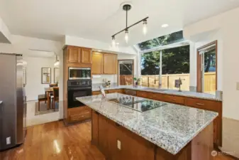 Refreshed kitchen with new countertops, cooktop, microwave, refrigerator and lighting.