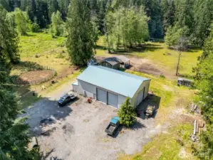 View of 40 x 60 shop with 36x40 loft with exterior entrance. Four 18' doors for drive through capabilities.  Hay barn, 3 stall loafing shed, 60' round pen, chicken coop, Shop has an a air compressor, mini split for heat/AC in the loft, stack washer and dryer, hot water heater, meat locker, refrigerator, freezer. Multiple pastures with gates. Easy parking and turn around capacity.