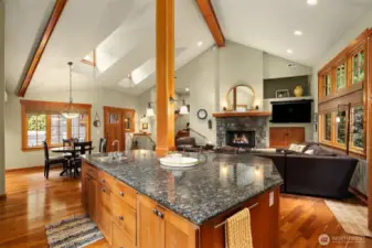 Oversized island in kitchen with bar seating flowing into living room with gas fireplace.