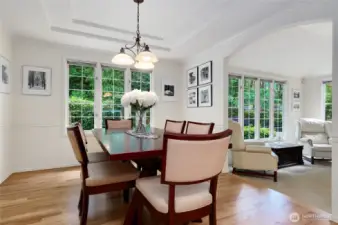 Sophisticated formal dining room with tray ceiling, and hard wood floors. An arched entry connects seamlessly to the formal living room, creating an elegant space for entertaining and gatherings.