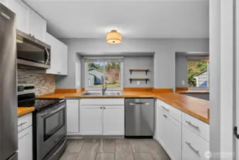 Kitchen boasts stainless steel appliances and butcher block countertops.