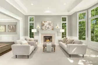 Formal living room with gorgeous fireplace has so many windows that let in the light and gorgeous greenery.
