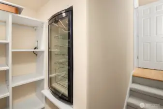 This home has an abundance of storage closets. This one under the stairs features a drinks fridge, built in shelving and wine racks (not shown) which will stay with the home.