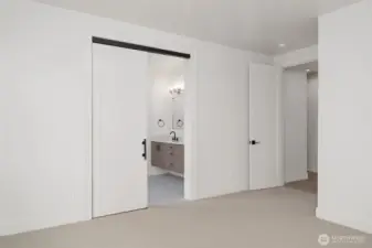 Contemporary barn door leads from Primary to the 5-pc bath