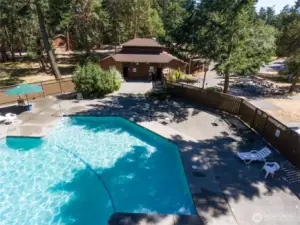 Community pool and clubhouse setting surrounded by mature evergreens, offering residents a peaceful retreat just moments from the waterfront.