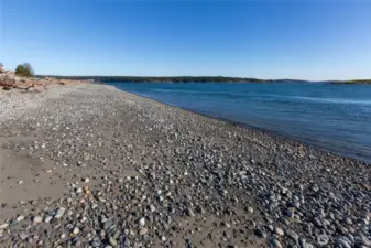 Long stretch of pebble shoreline with calm waters, offering a serene setting for beachcombing, kayaking, and enjoying island sunsets.