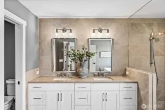 Dual vanities back with extensive sophisticated & quiet tile that runs through the shower as well.