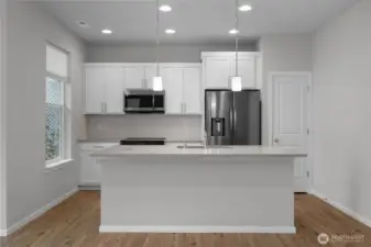 Modern kitchen featuring stone countertops, stainless steel appliances, and a large island with seating.