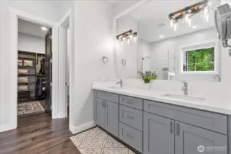5 piece primary bath with quartz throughout, double sinks, separate toilet area leading to custom shelving in massive walk in closet.
