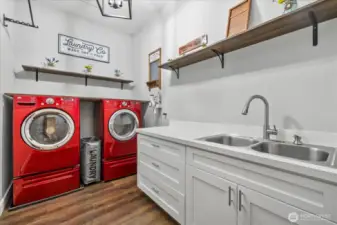 Laundry area offers double stainless sink with pull out sprayer wand and soap dispenser.  Folding counter, abundance shelving and hanging clothing rack.