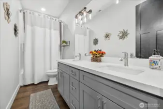 Main bathroom offers tub with shower niche cubby, 2 sinks with quartz countertops.
