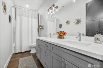 Main bathroom offers tub with shower niche cubby, 2 sinks with quartz countertops.