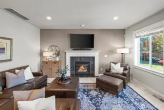 Open-concept family room in Horizon West home for sale in North Gig Harbor featuring a gas fireplace, large windows overlooking the fenced backyard, and seamless flow to the kitchen and casual dining area—ideal for everyday Northwest living.