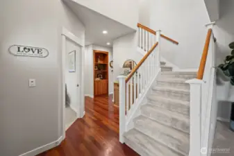 Stairwell view in Horizon West home for sale in North Gig Harbor showing the open layout with sightlines to the main floor hallway leading to the office, laundry room, and powder bath—designed for functionality and connected living.
