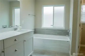 Primary bathroom suite with dual vanity sinks and tub