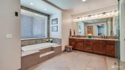 This primary en suite bath features large soaking tub and dual sink vanity with high end finishes throughout. Just through the bathroom find a massive walk-in closet in this en suite with private and secure safe/vault room