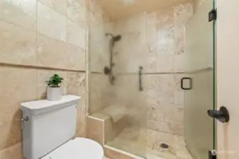 Primary shower with heated travertine floors, shower floor and seat are also heated.