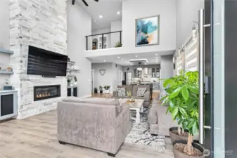 Open concept living room with gas fireplace stacked stone work floor to ceiling.