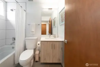 A guest bathroom featuring a tub, shower, and single vanity offers comfort and easy access for everyday use or visiting guests.