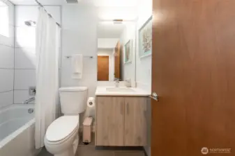 A guest bathroom featuring a tub, shower, and single vanity offers comfort and easy access for everyday use or visiting guests.