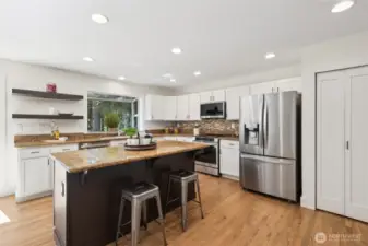 Stylish kitchen with crisp white cabinetry, a central island, and open shelving for display.