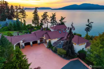From above, the estate reveals its full grandeur, a nearly two-acre waterside setting bathed in the glow of the evening sun.