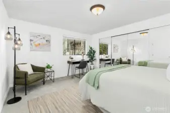 Main bedroom, aka bedroom number one, is super spacious! It's got room for a queen bed, a comfy sitting area with a chair and table, and a desk with a chair – perfect for working or relaxing.