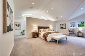Sumptuous primary suite with cathedral ceilings, skylights in the walk-in closet, seating area and custom built-in with beverage cooler.