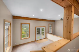 A couple of steps below the primary, is the loft/sitting area with french doors to the deck.