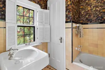 Beautifully preserved 100-year-old primary bathroom, showcasing historic details and timeless character with shutters for privacy and wonderful original tiles.