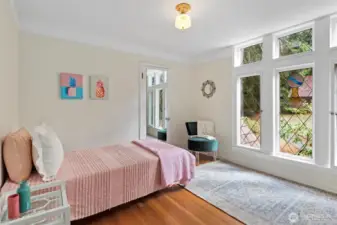 This bedroom features a trio of stained glass windows that fill the space with natural light and showcase historic charm. (and an en suite bathroom)