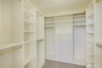 Primary closet with built-in shelves and cabinets